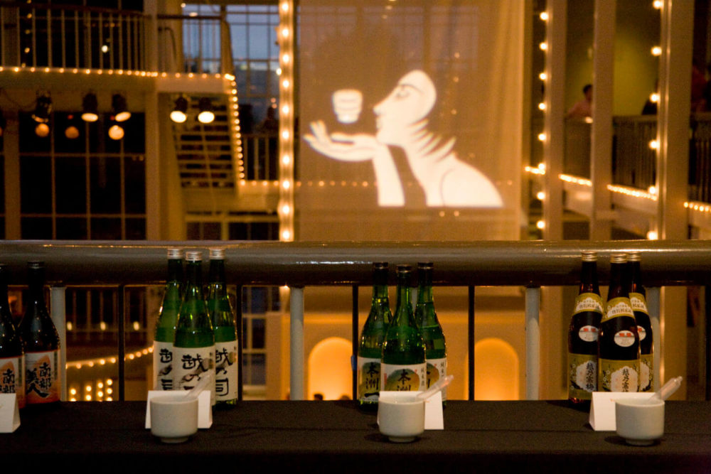 jos08sf048 Sake sampling table on the second floor across from the projected Sake Chick illustation (2008 San Francisco)
