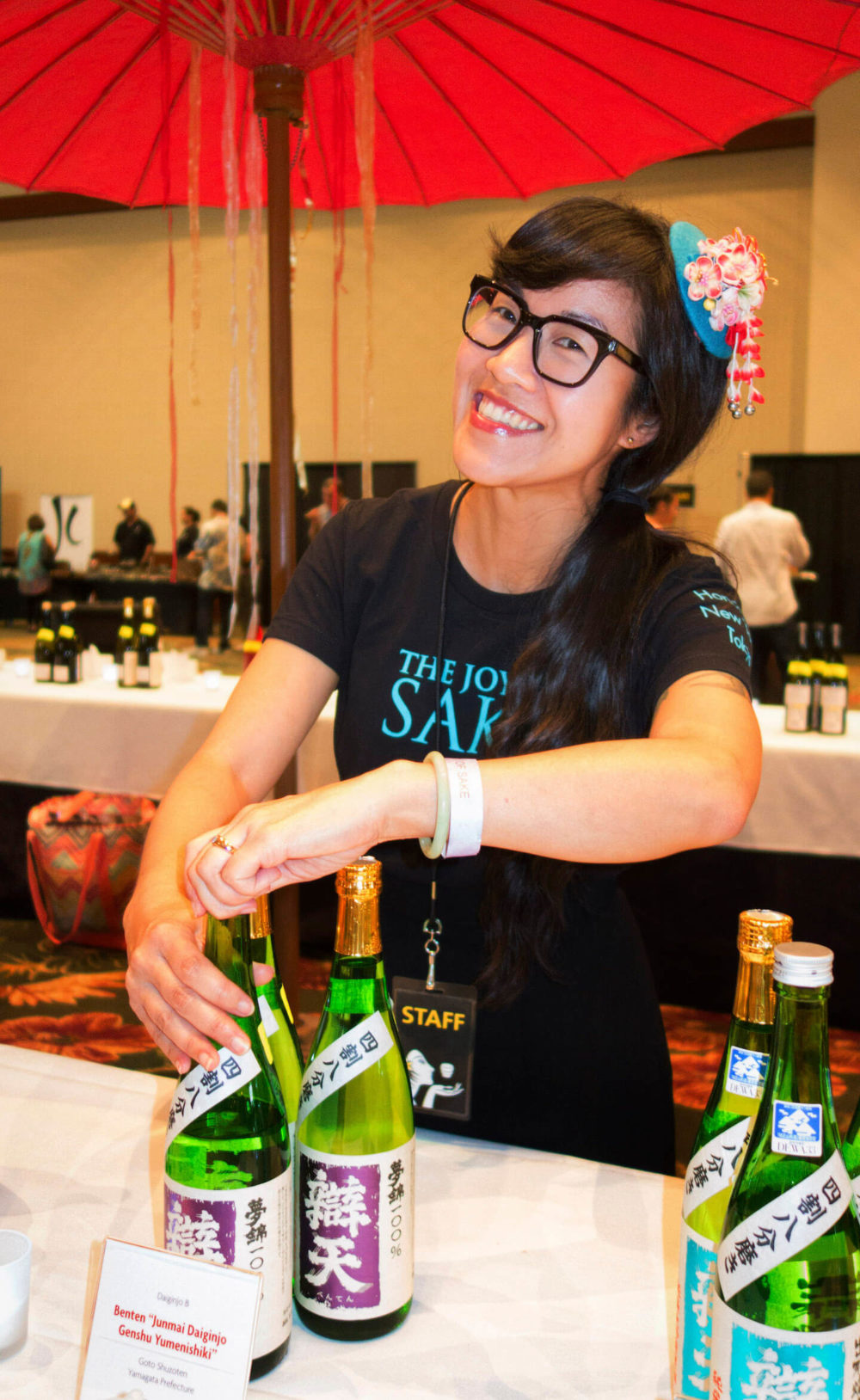 jos16hi005 A female volunteer opening a sake bottle with a smile (2016 Honolulu)