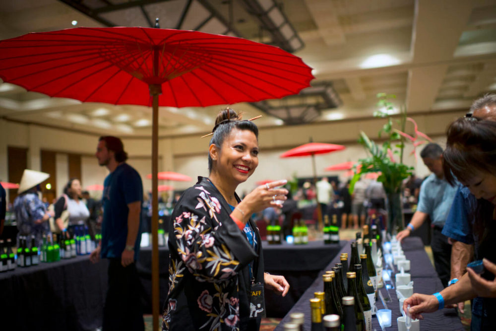 jos18hi002 A friendly female volunteer toasting inside of the booth (2018 Honolulu)
