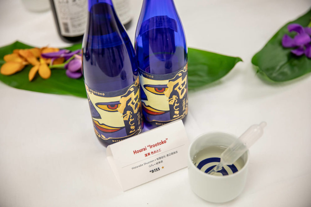 jos19tk264 Two blue bottles of Hourai Irootoko, a janome and a pipette with ti leaves and orchids behind (2019 Tokyo)