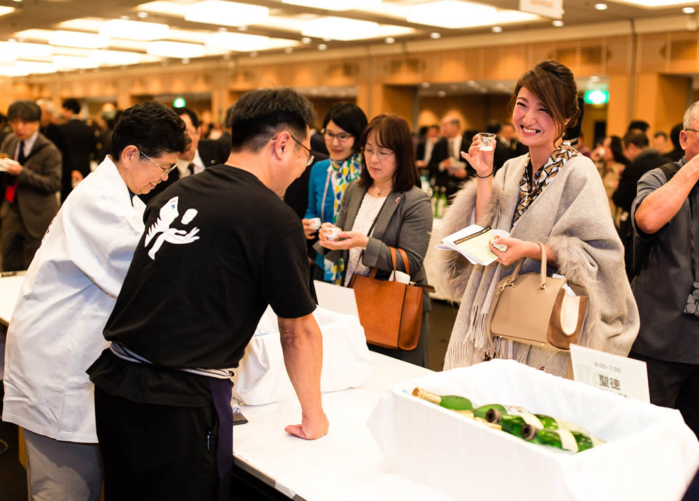 jos16tk291 An elegant lady holding a cup smiling and chatting at the sponsor booth (2016 Tokyo)