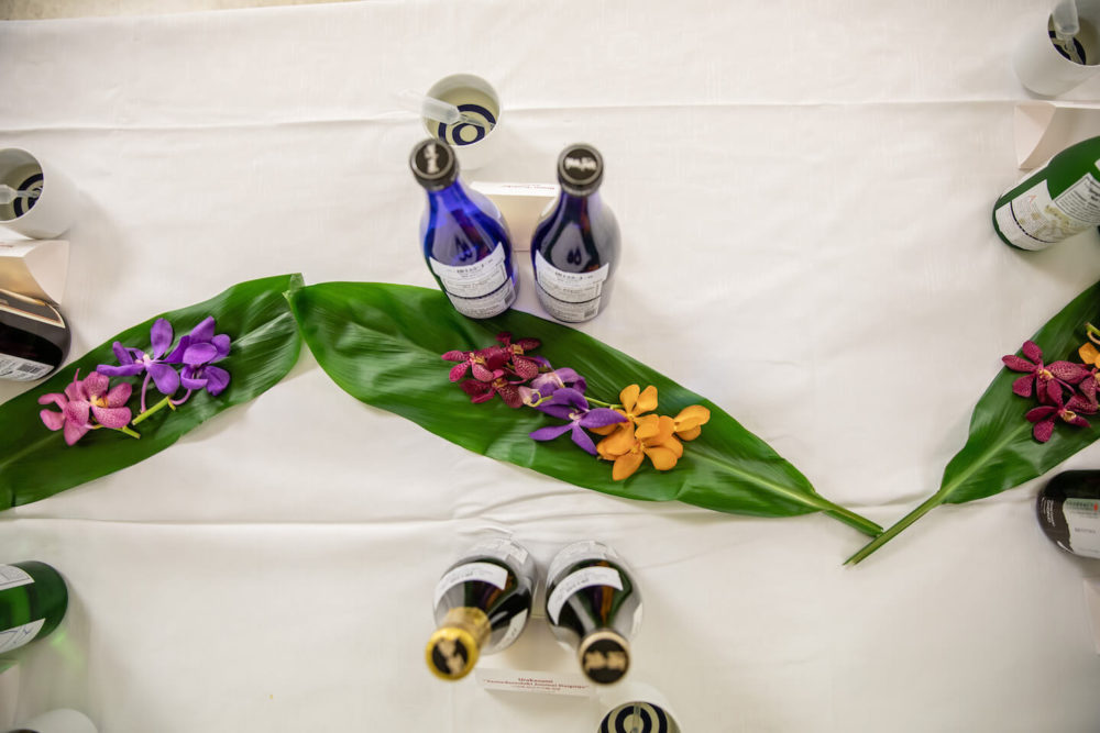 jos19tk249 View from above of bottles on the table with ti leaves and orchid flowers (2019 Tokyo)